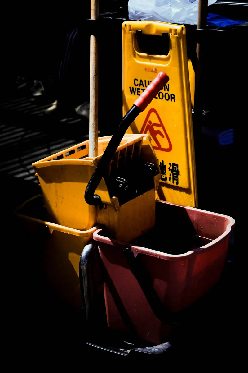 Yellow mop bucket and red bucket with a wet floor sign